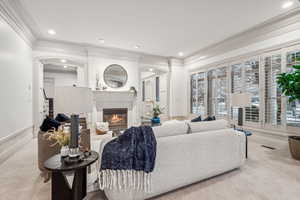 Carpeted living room with a fireplace and crown molding