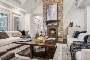 Living room featuring hardwood / wood-style floors, ornamental molding, a fireplace, and high vaulted ceiling