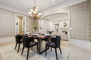 Dining room with light colored carpet, crown molding, and a notable chandelier