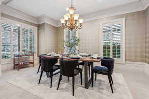 Dining room with light colored carpet, an inviting chandelier, and crown molding