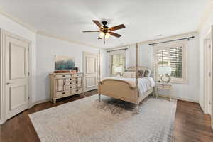 Bedroom with ceiling fan, crown molding, and dark hardwood / wood-style floors