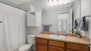 Bathroom with curtained shower, vanity, and toilet