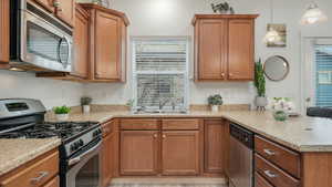 Kitchen with kitchen peninsula, pendant lighting, sink, and stainless steel appliances