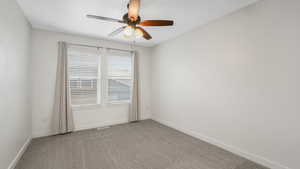 Carpeted spare room featuring ceiling fan