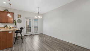 Kitchen with a kitchen bar, hardwood / wood-style floors, a chandelier, and decorative light fixtures