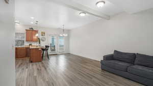 Living room with beam ceiling, an inviting chandelier, and light hardwood / wood-style flooring