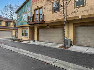 View of property with a balcony, a garage, and cooling unit