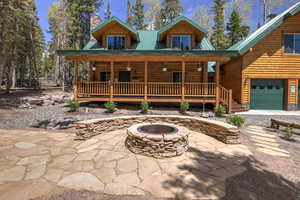 Log cabin with covered porch, a fire pit, and a garage