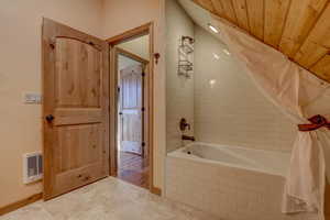 Bathroom with hardwood / wood-style floors, shower / tub combo with curtain, and wood ceiling