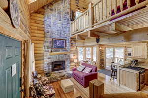 Living room with a fireplace, light wood-type flooring, high vaulted ceiling, and wooden ceiling