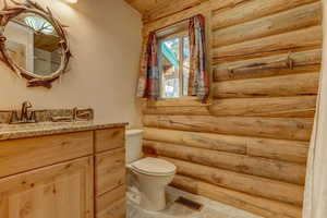 Bathroom with rustic walls, vanity, and toilet