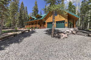 Log cabin featuring a porch and a garage