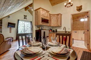 Dining space featuring sink, lofted ceiling with beams, light hardwood / wood-style flooring, and wood ceiling