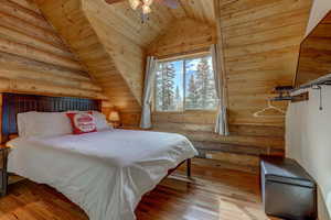 Bedroom featuring wood ceiling, rustic walls, ceiling fan, and wood-type flooring