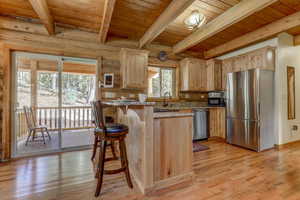 Kitchen featuring appliances with stainless steel finishes, light hardwood / wood-style floors, light brown cabinetry, and wood ceiling