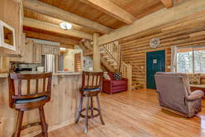 Kitchen with a breakfast bar, light wood-type flooring, stainless steel refrigerator, and wooden ceiling