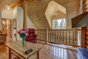 Living area with a chandelier, high vaulted ceiling, light hardwood / wood-style flooring, and wood ceiling