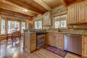 Kitchen with light stone countertops, stainless steel appliances, kitchen peninsula, wood ceiling, and light wood-type flooring