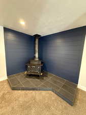 Details with carpet flooring, a wood stove, and a textured ceiling