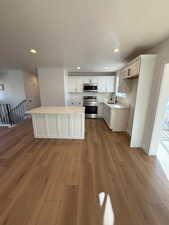 Kitchen featuring light wood-type flooring, stainless steel appliances, white cabinetry, and sink