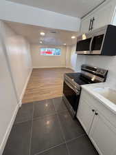 Kitchen with white cabinetry, dark wood-type flooring, light stone counters, and appliances with stainless steel finishes