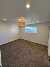 Unfurnished room with dark colored carpet and a textured ceiling