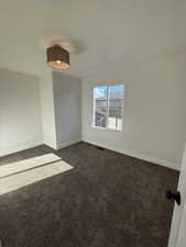 Carpeted spare room featuring a textured ceiling