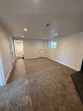 Basement with a textured ceiling and dark carpet