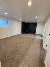 Basement with a wood stove and carpet floors