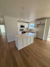 Kitchen with white cabinets, light wood-type flooring, stainless steel appliances, and sink