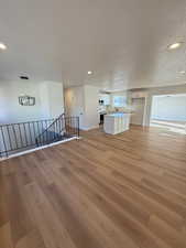 Unfurnished living room featuring light hardwood / wood-style flooring, a textured ceiling, and sink