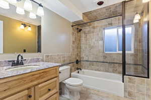 Full bathroom with vanity, tile patterned floors, tiled shower / bath combo, toilet, and a textured ceiling