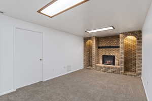 Unfurnished living room featuring carpet flooring and a brick fireplace