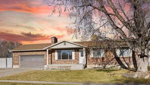 Single story home with a garage and a lawn