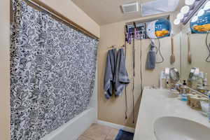 Bathroom featuring vanity, a textured ceiling, tile patterned floors, and shower / bath combo with shower curtain