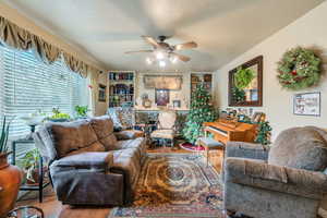 Living room with ceiling fan, a textured ceiling, and hardwood / wood-style flooring