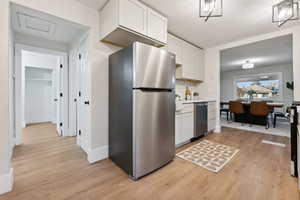 Kitchen with white cabinets, stainless steel fridge, and light hardwood / wood-style floors