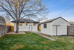 Back of property featuring a lawn, an outdoor structure, and a patio