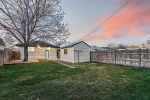 Yard at dusk with a storage unit and a patio