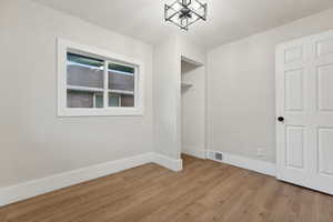 Unfurnished room with a chandelier and light wood-type flooring