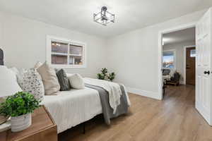 Bedroom with an inviting chandelier, light wood-type flooring, and multiple windows