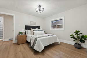 Bedroom with a chandelier and light hardwood / wood-style floors