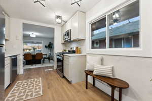 Kitchen with white cabinetry, stainless steel appliances, and light wood-type flooring