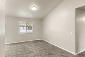 Carpeted empty room with vaulted ceiling