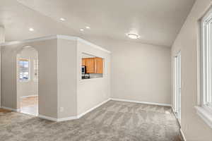 Unfurnished room featuring light colored carpet and lofted ceiling