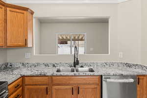 Kitchen featuring light stone countertops, sink, and appliances with stainless steel finishes