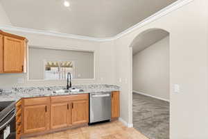 Kitchen with sink, stainless steel dishwasher, ornamental molding, light colored carpet, and range