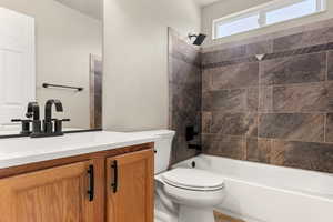 Full bathroom with tiled shower / bath combo, toilet, and vanity