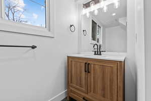 Second bathroom with wood colored vanity and a healthy amount of sunlight