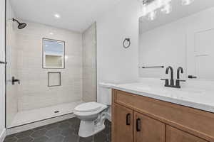 Bathroom with tile patterned floors, modern wood vanity, and a tile shower.